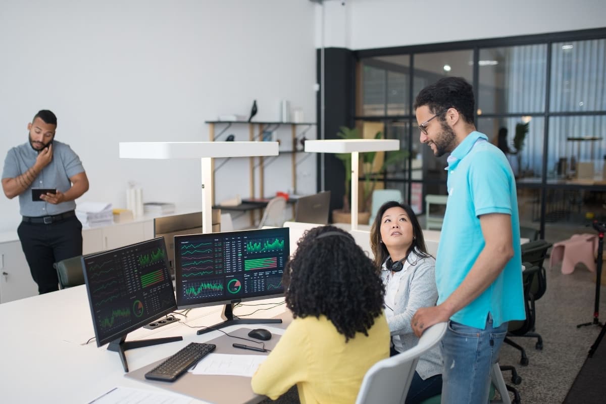 An operations team reviewing system-health dashboards across multiple monitors