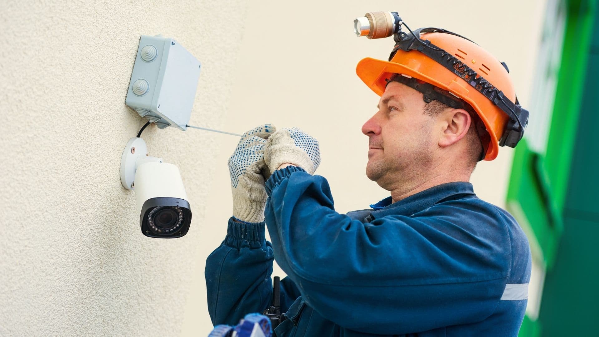 A technician mounting an exterior surveillance camera to a building wall